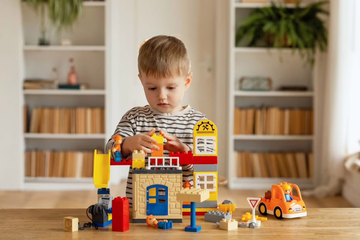 Garçon de 4 ans qui joue avec des briques de construction à la maison