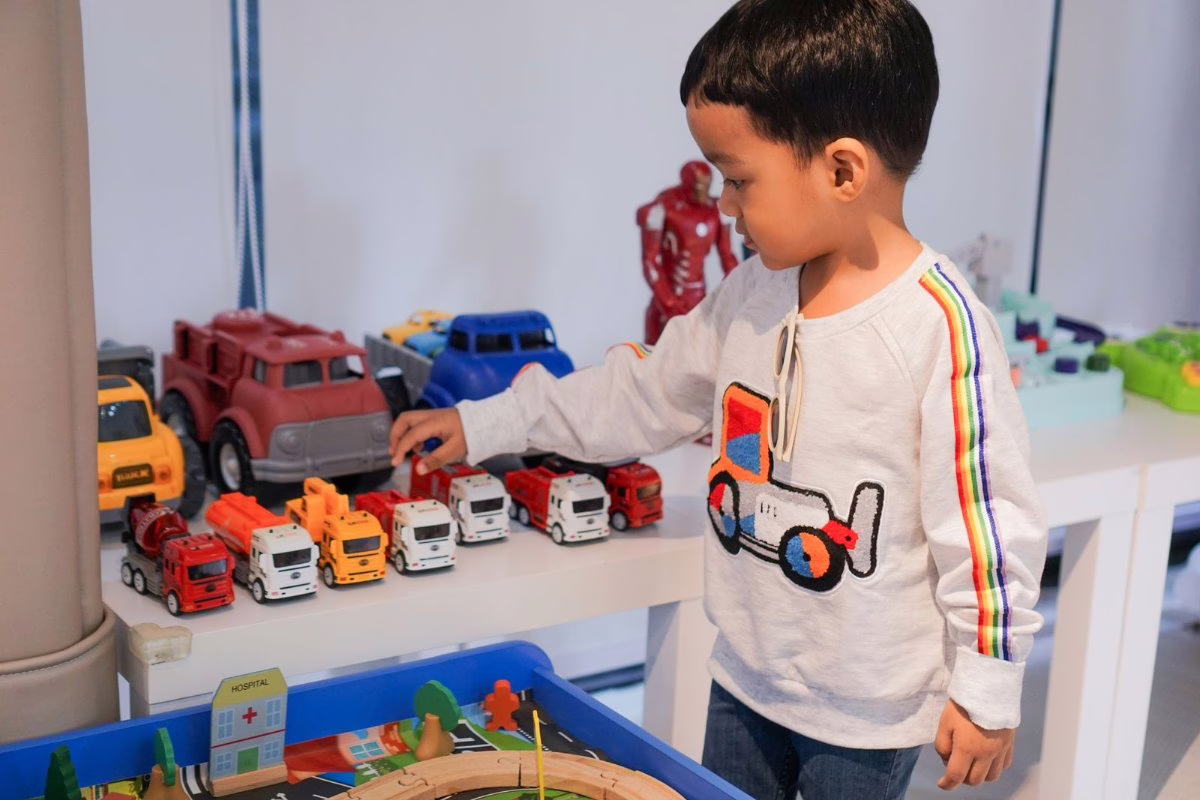 Garçon de 5 ans qui joue avec ses camions de pompiers