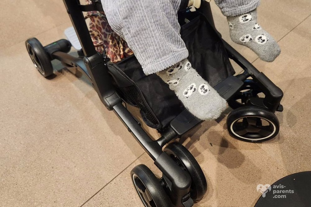Les pieds de l’enfant dépassent du repose-jambes de la poussette Piko