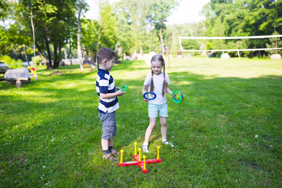 Deux enfants jouent à un jeu d'adresse de lancer en extérieur dans un parc ensoleillé